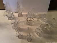 Full view of 10 assorted crystal and glass basket design vases with various cuts and patterns shown on a light surface