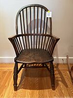 Front view showing chair's curved spindle back, arms, contoured seat, and turned legs.