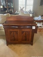 Full front view of mahogany storage cabinet with double doors and raised back trim board.
