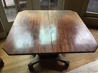 Top view of square mahogany table showing wood grain, folding seam in center, and weathered surface.