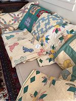 Overview of six finished quilts draped on a sofa showing variety of patterns