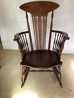 Front view showing carved backrest, spindle arms, contoured seat and rockers.