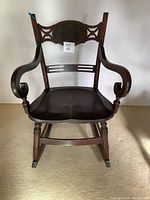 Front view showing the full chair including the contoured seat, decorative backrest with cutouts, and curved scroll armrests.