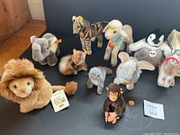 Group of Steiff plush animals arranged on black background.