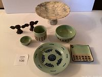 Full view of the vintage Asian tableware set with marble cake stand and iron decorative pieces arranged on a white surface.