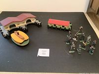 Overview photo showing both wooden docks, the wooden boat, and the twelve metal figurines grouped together