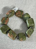 Top-down view of the full bracelet showcasing the green and pink Unikite stones alternated with metal beads.