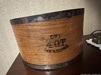 Side view of wood measuring bowl showing 'Dry 4 QT Measure' stamped on side with metal rims on top and bottom.