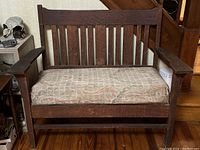 Front view of bench showing slatted back, squared arms and upholstered seat.