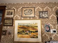 Wall display of six framed art pieces including a large watercolor landscape and smaller prints.