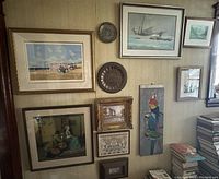 Overview of wall display with multiple framed artworks and two decorative plates