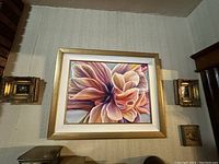 Six artworks arranged on wall including a large floral painting flanked by smaller framed pieces