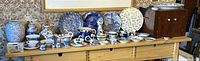 Full view of the collection on a shelf, showing numerous blue and white pottery and ceramic items including plates, pitchers, teapots, and bowls.