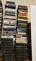 Stacks of various hardcover and paperback books arranged upright and stacked horizontally.