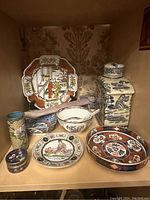 Full view of the shelf with all Chinese ceramic items arranged showing varied shapes and intricate painted designs.
