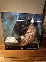 Front cover of Star Wars laserdisc showing iconic movie poster art with lightsabers, starships, and characters.