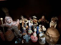Wide view showing assortment of Mexican figures, dolls, pottery and art objects arranged on a wooden surface.