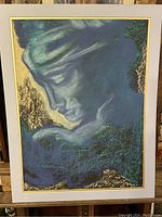 Front view of original framed artwork depicting a woman's profile in blue, green, and gold hues. The piece is matted in white with a gold inner border.
