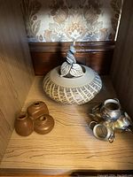 Display shelf containing the pottery and metal jug sculpture showing all items.