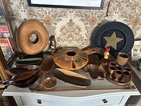 Overview of collection of wooden art objects including bowls, trays, sculpture, spoons, cups, and boomerang.