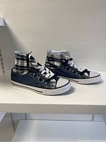 Side view of the dark blue denim high-top sneakers showing the plaid interior lining and white laces.