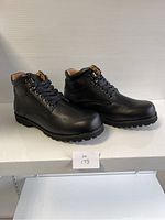 Side view of the pair of black men's comfort shoes on display showing smooth leather-like surface, laces, padded collar, and lug soles.