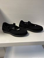 Side angle view of black Orthofeet ladies shoes showing the mesh upper and Velcro strap.