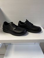 Pair of black Orthofeet men's leather shoes displayed side by side at slight angle showing outer sides and profile.