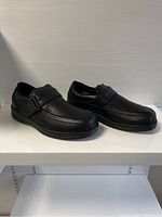 Side angle view showing both shoes, highlighting the strap closure and decorative perforations.