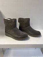 Front and side view of grey suede UGG boots with wedge soles.