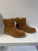 Side angle view of the tan UGG boots highlighting the rounded toe and sole design.