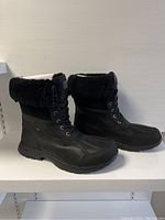 Side profile of both boots showing exterior upper materials and shearling cuff.