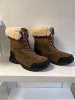 Side profile of both boots showing suede exterior and shearling collar.