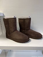 Side view of pair of brown UGG Classic Short boots, soft suede material, showing shape and height