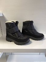 Side view of both unisex winter boots, black with thick rugged soles and fleece lining.