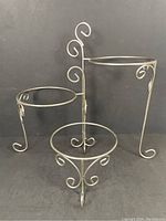 Front angle showing three circular tiers and decorative scrollwork in black metal.