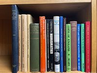 Shelf with 13 vintage coin and token collecting books, various colors and titles, generally in good condition.