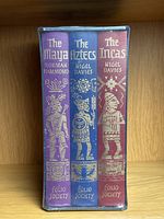 Front view of the three book spines from the Folio Society set, showing titles and author names with gold embossed illustrations on blue, purple and red backgrounds.