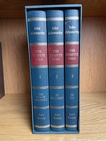 Three hardcover books in slipcase, title The Forsyte Saga by John Galsworthy. Volumes numbered 1 to 3 with individual titles on spine. Blue cloth bindings with gold text and red labels.