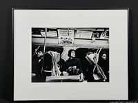 Framed black and white photograph showing four passengers on a NYC subway, three clearly visible and one behind newspaper.