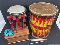 Front view showing the djembe, painted wooden drum, tambourine, carved block, and ocarina flute
