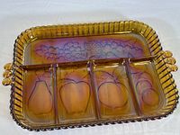 Top-down view of the amber-colored carnival glass snack tray showing four compartments with fruit motifs and fluted edges with beaded rim.