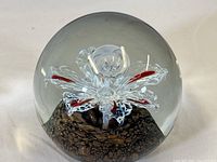 Full view of one Murano glass paperweight showing flower design inside clear glass dome with textured base.