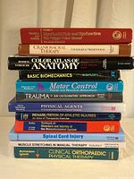 Stack of 12 orthopedic and anatomy textbooks visible with full titles on spines.