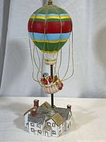 Front view of the colorful hot air balloon music box with clown in basket and house-shaped base