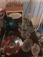 Wide view of punch bowl set box with bowl, large snifter and various glass trays and cups on table