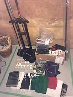 Photo taken showing golf stand, boxed golf balls, golf gloves, tees, towels, and ball retriever.