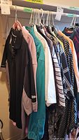 Image showing a row of men's golf shirts hanging on hangers. Assorted colors and patterns visible, mostly collared shirts suitable for golf or casual wear.