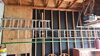 Two aluminum ladders mounted horizontally against wood stud wall