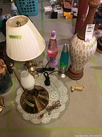 Wide view of five lamps showing relative scale: two lava lamps, a tall ceramic lamp, a glass candle lamp and a brass lamp with fabric shade